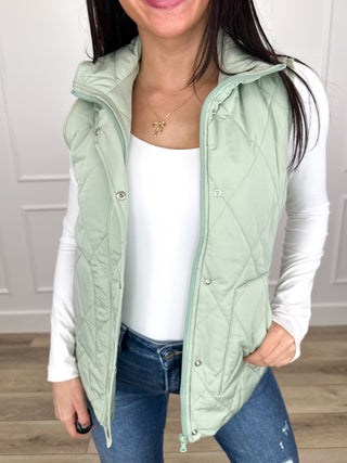 Sage green quilted puffer vest with snap-button front and hooded collar