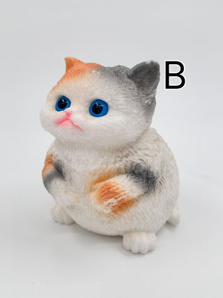 White and gray plush squishy cat with blue eyes, orange markings, sitting