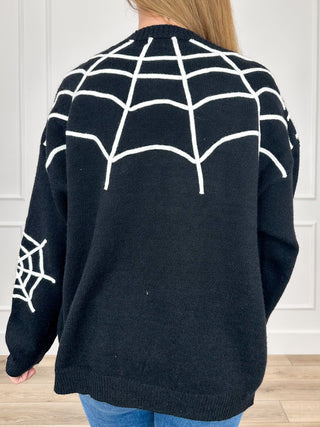 Black knit cardigan with white spiderweb pattern on back, long sleeves