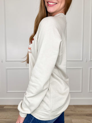Oat crewneck sweatshirt side view, long sleeves with partial Faithful text