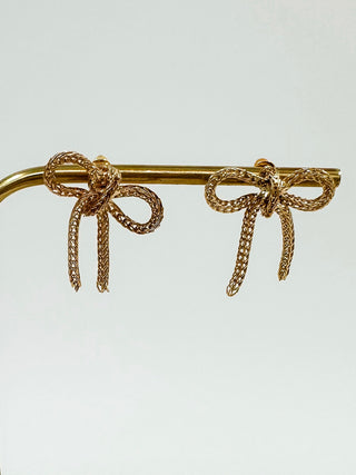 Gold ribbon bow drop earrings with long dangling strands on metal bar