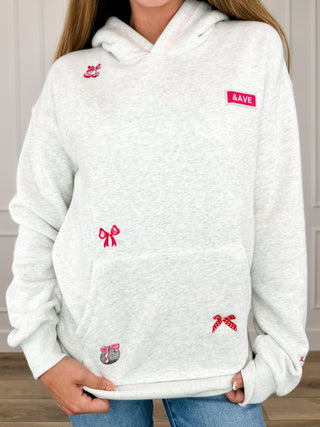 Light grey hoodie with hood, long sleeves, front pocket, red bow and logo patch