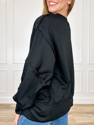 Black long-sleeve top with drop shoulder sleeves and loose relaxed fit.