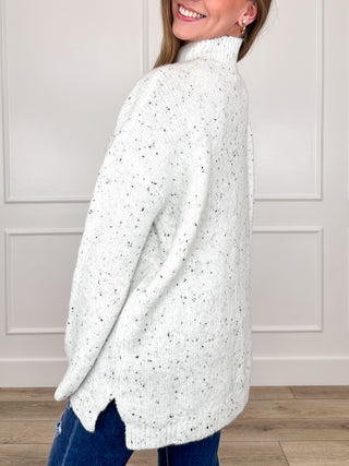 White speckled knit turtleneck sweater with long sleeves, side view