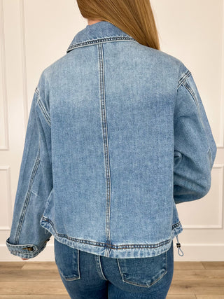 Medium wash cropped denim jacket, back view with yoke seam and button cuffs, long sleeves