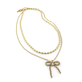 Gold dangling bow necklace with crystal bow pendant and fine layered chain links.