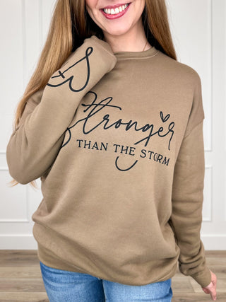 Brown long-sleeve crewneck sweatshirt with 'Stronger than the storm' graphic