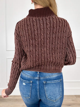 Brown cable-knit turtleneck sweater with long sleeves, ribbed neckline and hem