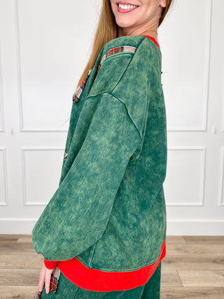 Green cotton long-sleeve top with red cuff trim and plaid bow detail on chest
