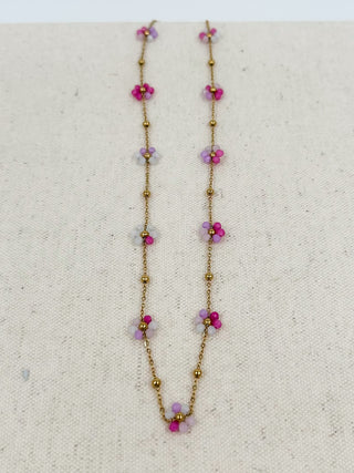 Gold beaded necklace with dangling purple flower charms and small pearl accents