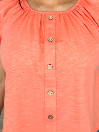 Coral orange cotton top close-up with button placket and rounded neckline
