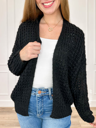 Black knit long-sleeve cardigan with open front and textured stitch.