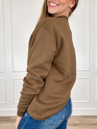 Brown crewneck sweatshirt side view with long sleeves and ribbed cuffs and hem