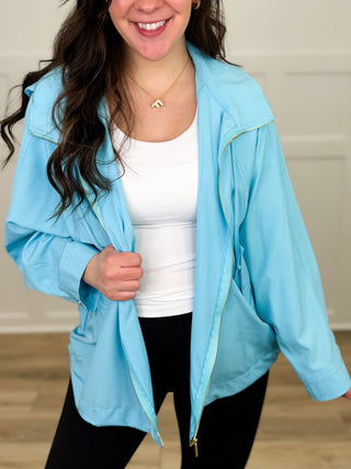 Light blue lightweight hooded jacket with front zipper and drawstring at hem