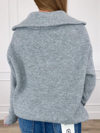 Back view of light grey knit quarter-zip sweater with raised collar and textured knit