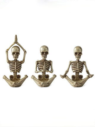 Gold resin skeleton decor figures in three poses, skull heads and ribcages visible
