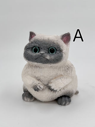 Gray plush squishy cat with green eyes, sitting with paws together