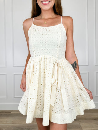 Cream cotton dress with thin straps, square neckline, eyelet bodice and gathered flounce hem