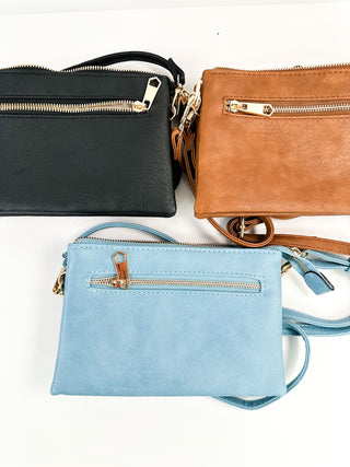 Assorted faux leather handbags in black, cognac brown, and light blue with top zips