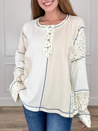 Ivory long-sleeve top with blue speckle trim, button placket, embroidered flower accents
