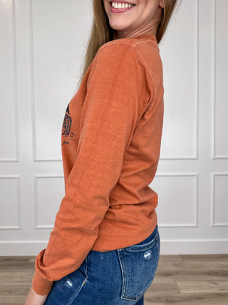Orange long-sleeve cotton tee with pumpkin wagon graphic, side view
