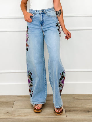 Light wash high-rise wide-leg jeans with floral embroidery down sides, side view