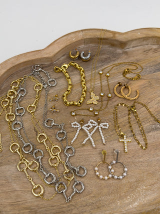 Assorted gold and silver-tone jewelry: bracelets, chains, earrings, rings on tray