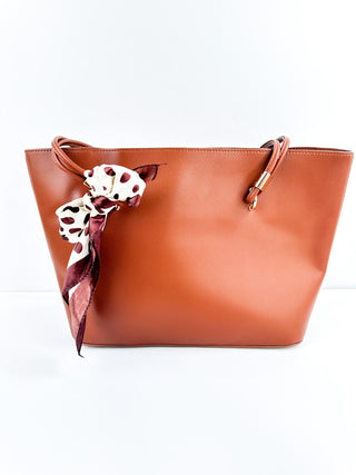 Terracotta faux leather tote bag with top handles and ribbon bow scarf charm