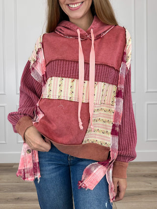 Burgundy hooded long-sleeve top with drawstring, front pocket, and multicolor patch sleeves