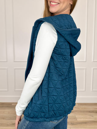 Blue quilted hooded vest, side view with layered hood and curved hem