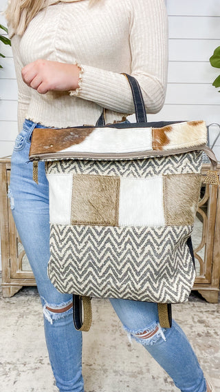Colorblock cowboy backpack with top flap, tan leather trim, zigzag chevron front pocket.