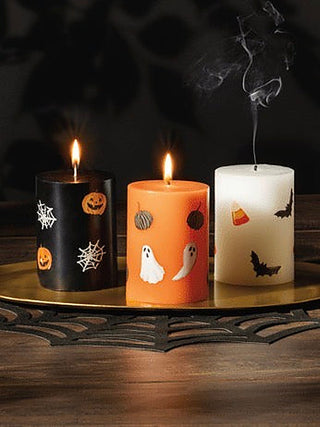 Set of three Halloween candles: black, orange, and white with spooky designs