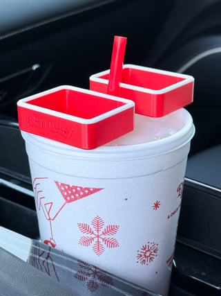 Red sauce cup with two lidded condiment holders and a straw on a patterned drink cup
