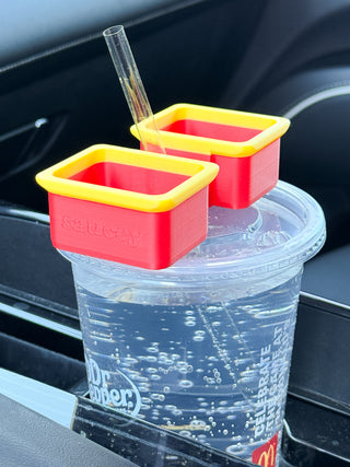 Yellow and red sauce cup set with straw and two condiment holders on a clear drink cup