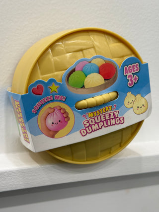Dumpling squishy toy in yellow dome packaging with colorful squeeze balls