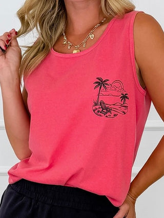 A woman wearing a pink sleeveless tank top with a black tropical beach graphic on the left chest, paired with black shorts and gold necklaces.