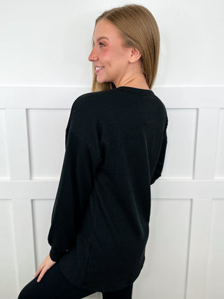 Black ribbed long-sleeve top, back view with crew neck and ribbed hem.