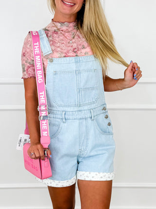 Light blue denim overall shorts, front bib, adjustable straps, button pockets, cuffed legs