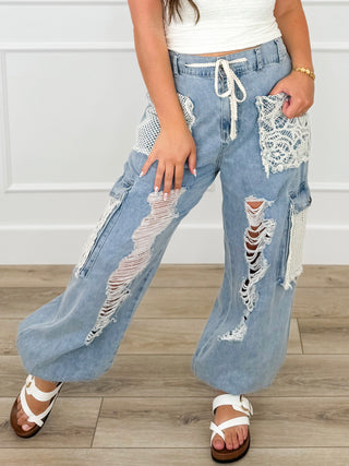 Light denim blue cotton cargo joggers with drawstring waist, ripped knees, and patch pockets.