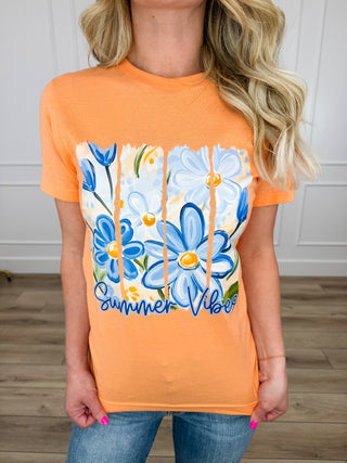 Person wearing an orange t-shirt with blue floral design and 'Summer Vibes' text.