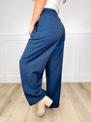 High-rise wide-leg dark wash denim jeans, angled side view with roomy legs