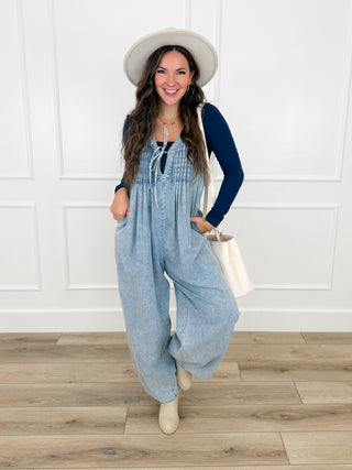 Light wash denim cotton-blend jumpsuit with long sleeves, wide-leg fit, front pockets