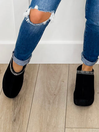 Black faux suede platform slip-on shoes with patterned trim and rounded toe