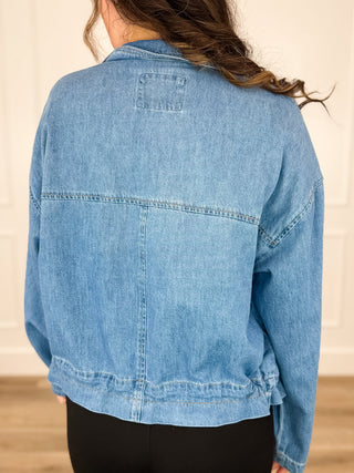 Medium wash denim jacket back with yoke seam and patch pocket detail