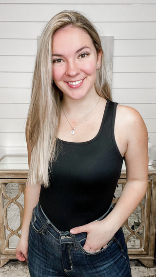 Black scoop-neck sleeveless bodysuit with fitted silhouette and snap crotch