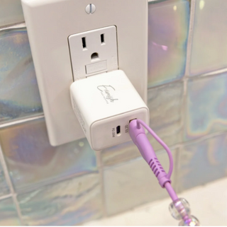 White charging cube adapter with USB ports, plugged into wall outlet.