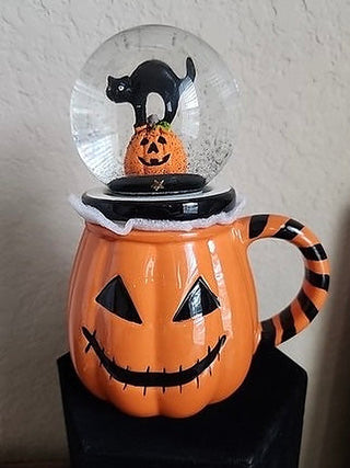 Orange ceramic globe mug with jack-o-lantern face and black cat in clear snow-globe lid