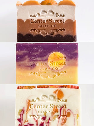 Three Center Street soap bars—orange, purple, and white—shown stacked