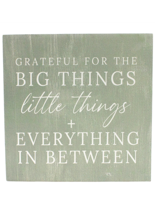 Green wood block sign with quote text: “GRATEFUL FOR THE BIG THINGS ... IN BETWEEN”