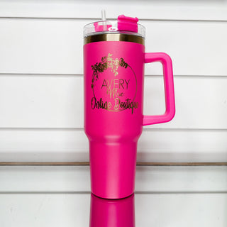 Hot pink gold-accent tumbler with clear lid, side handle, and front logo.